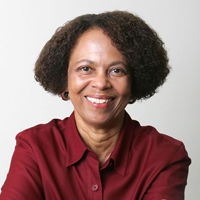 A photograph of Professor Leith Mullings.  She is smiling, wearing a red shirt.